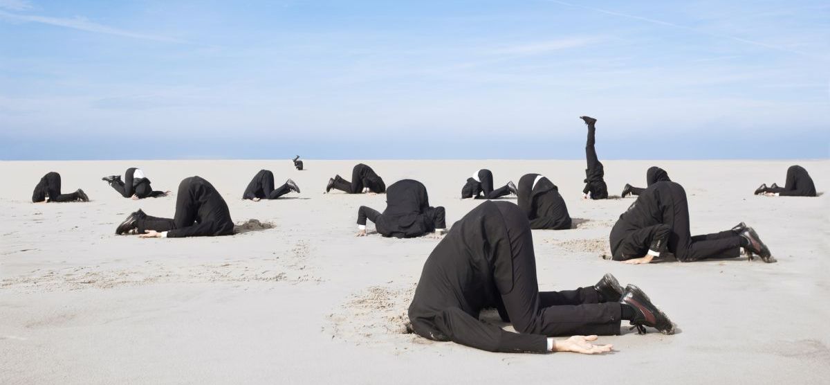 Lots of business man hiding their heads in sand. XXL size image. Bild: © istock.com / Jan-Otto