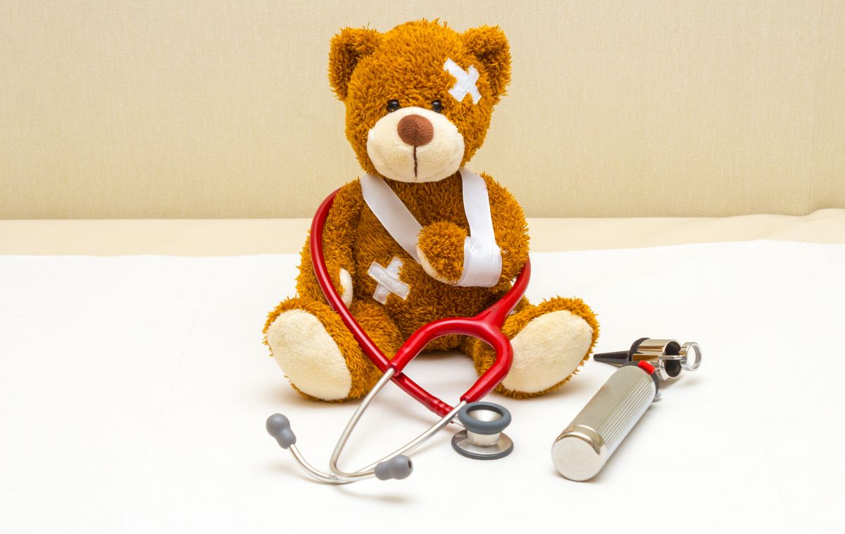 Brown teddy bear with bandages and broken hand in pediatrician's office. Bild: © istock.com / catalinr