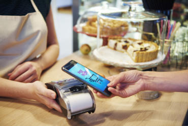 Kundin hält ihr Handy über ein Lesegerät im Café, um zu zahlen