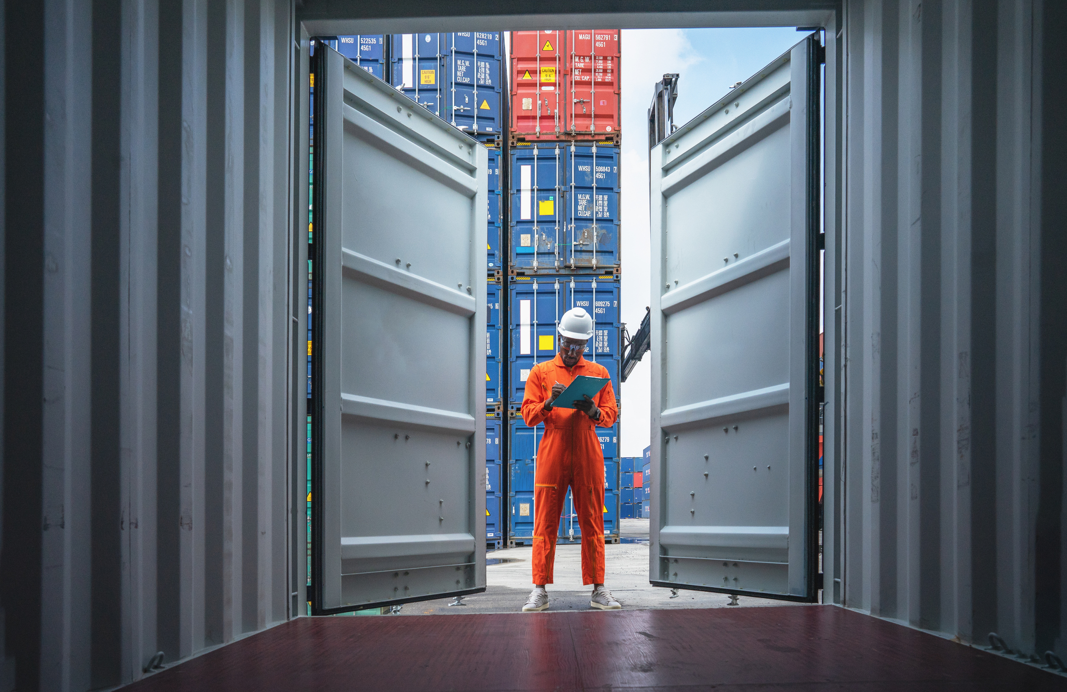 Logistik / Import / Export: Container auf einem Frachtschiff werden von einem Arbeiter kontrolliert
